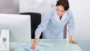 Portrait Of Happy Female Janitor Cleaning Desk At Office